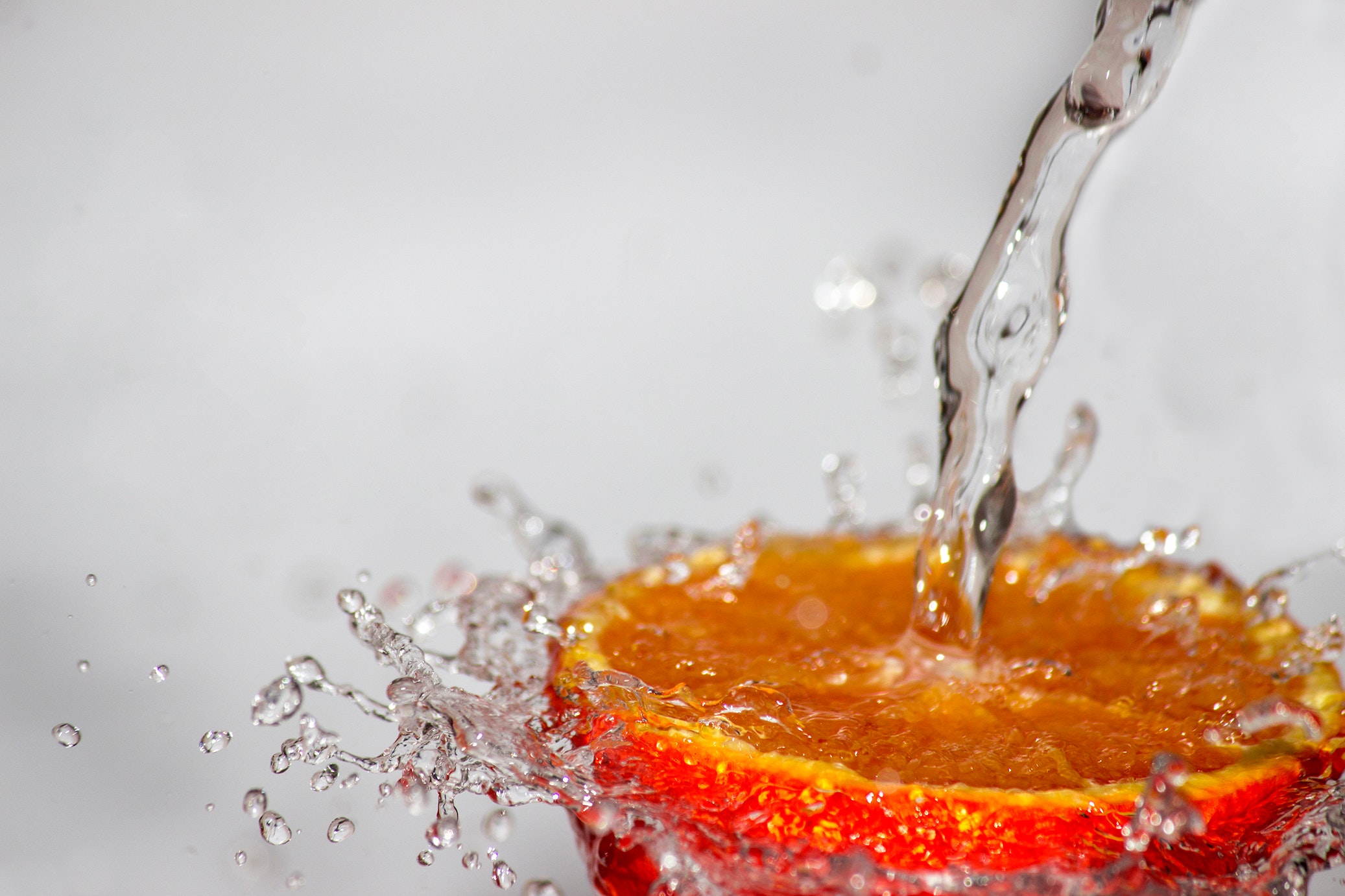 Wasserstrahl spritzt auf Orangenscheibe